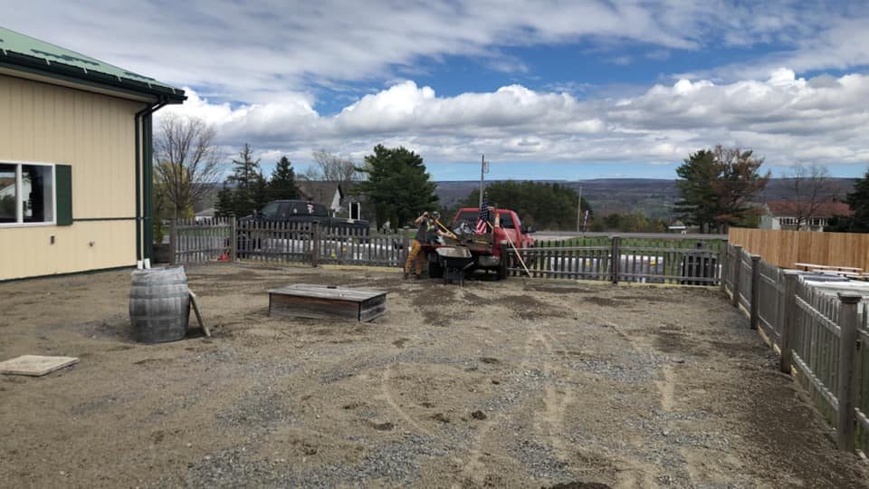 Patio hardscape worksite with materials and equipment beside a building