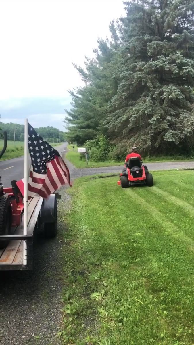 Zero-turn mower cutting a rural roadside lawn
