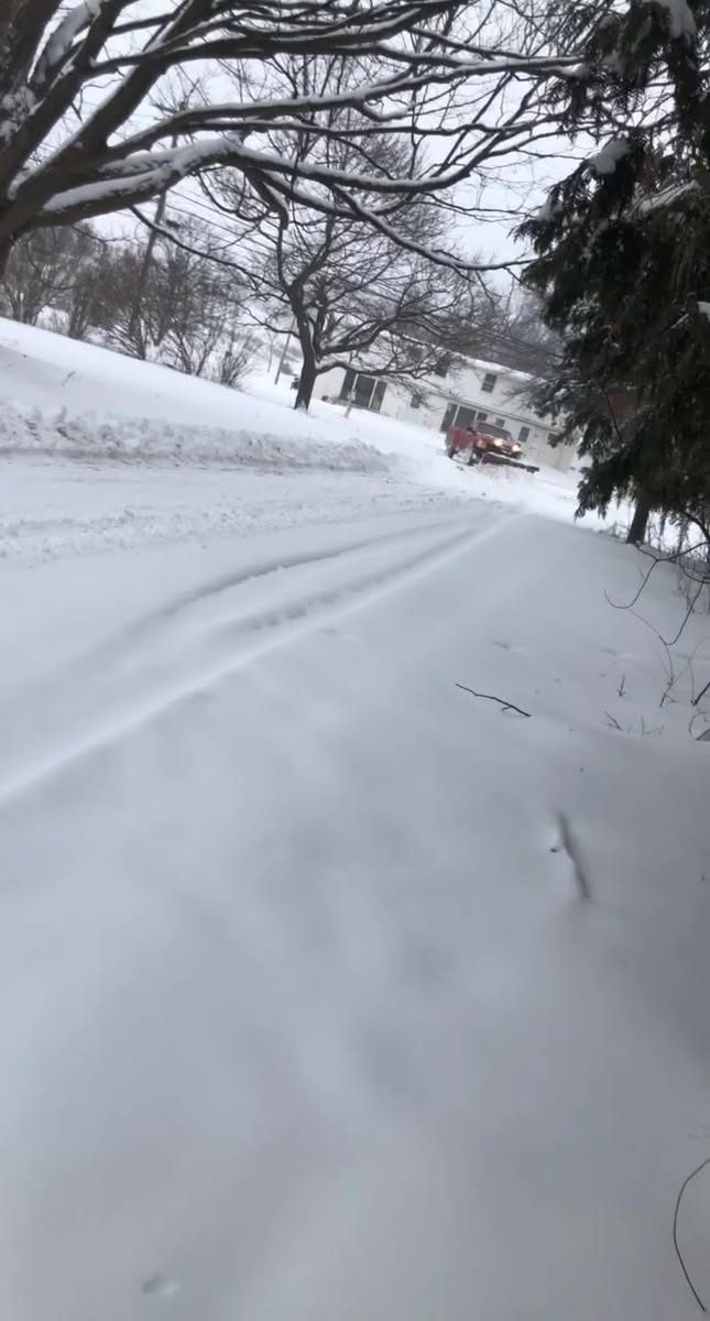 Truck plowing a snowy driveway or road from a distance